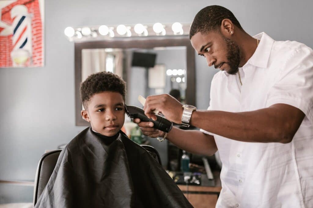 Man giving boy a hair cut to donate a service to foster children in Arkansas