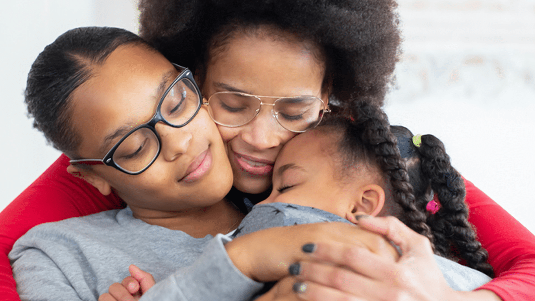 Mother holding her young child and teenager