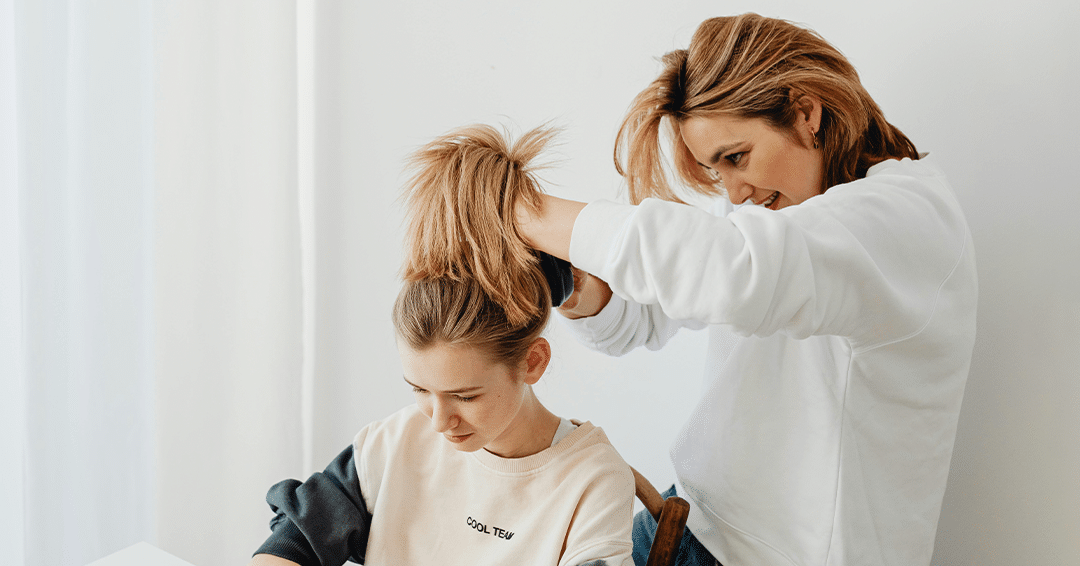 Foster care adult styling a foster child's hair in a bright home environment, highlighting supportive relationships.